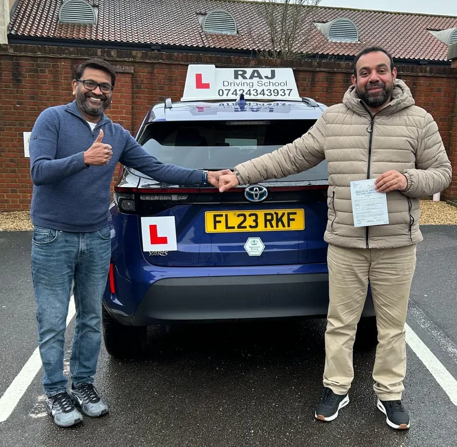 Raj shaking hands with a newly qualified student beside the lesson car
