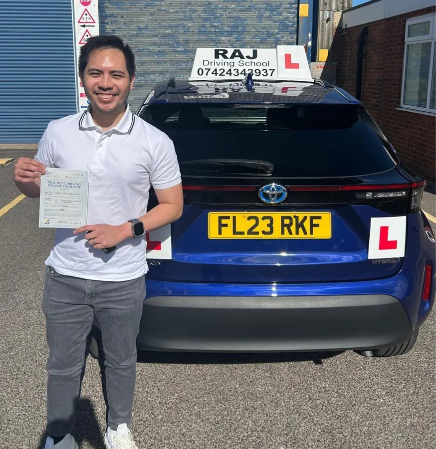 A student holding their driving test pass certificate beside Raj's Toyota Yaris Cross