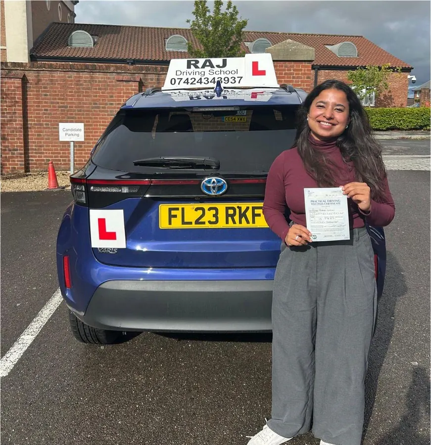 A student holding their driving test pass certificate beside Raj's Toyota Yaris Cross