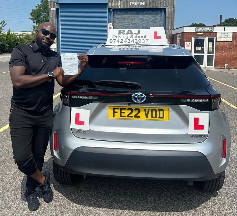 A student holding their driving test pass certificate beside Raj's Toyota Yaris Cross