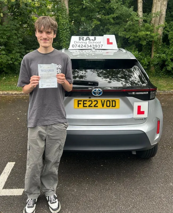 A student holding their driving test pass certificate beside Raj's Toyota Yaris Cross