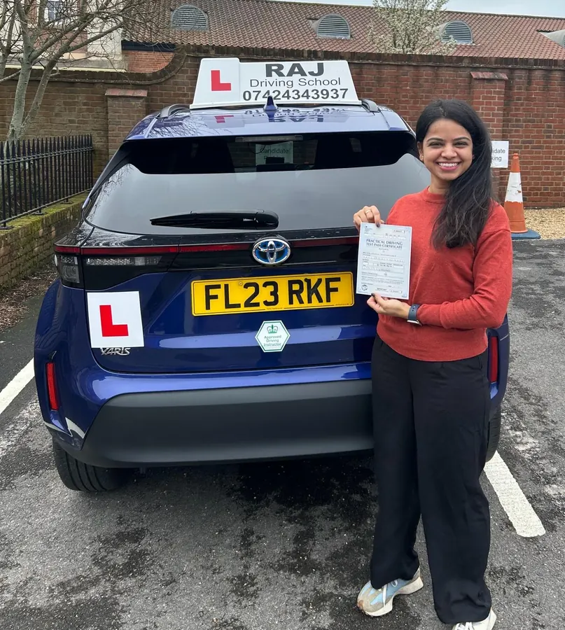 A student holding their driving test pass certificate beside Raj's Toyota Yaris Cross
