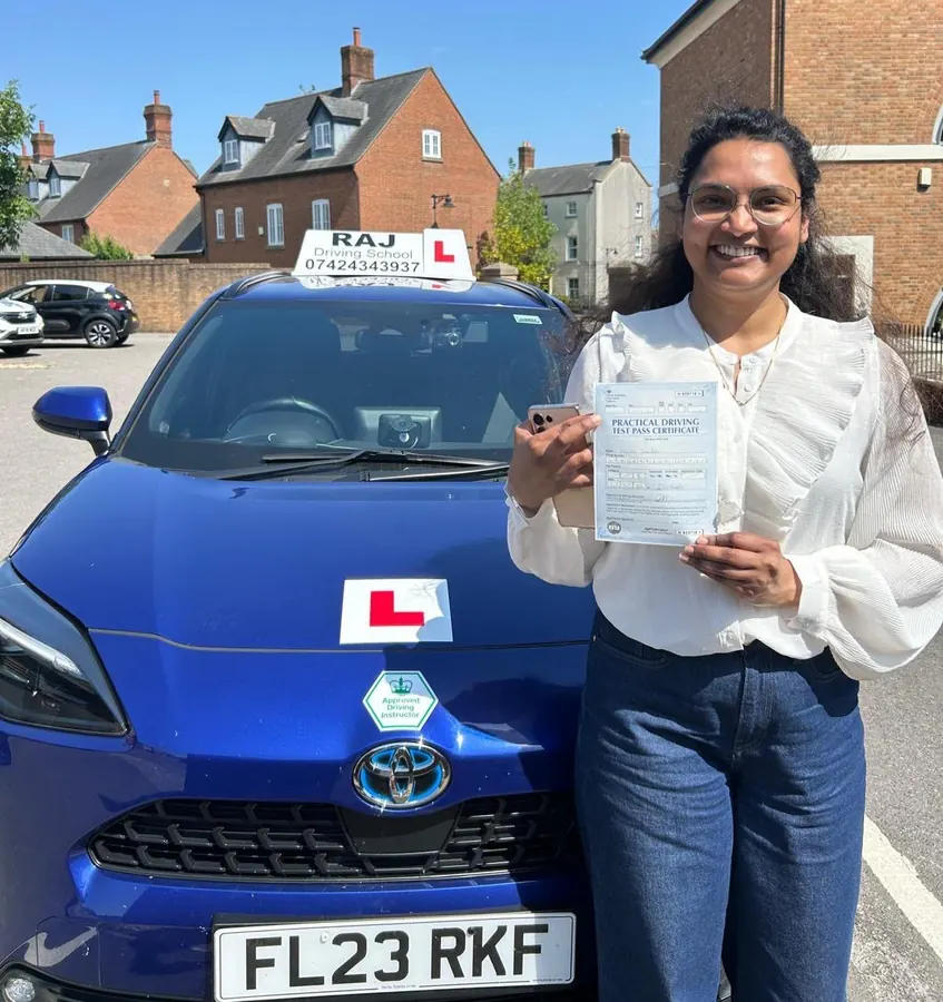 A student holding their driving test pass certificate beside Raj's Toyota Yaris Cross