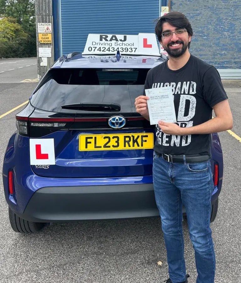 A student holding their driving test pass certificate beside Raj's Toyota Yaris Cross