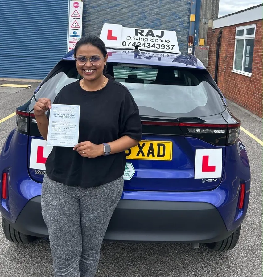 A student holding their driving test pass certificate beside Raj's Toyota Yaris Cross