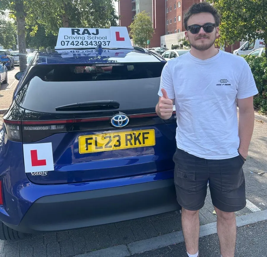 A student holding their driving test pass certificate beside Raj's Toyota Yaris Cross