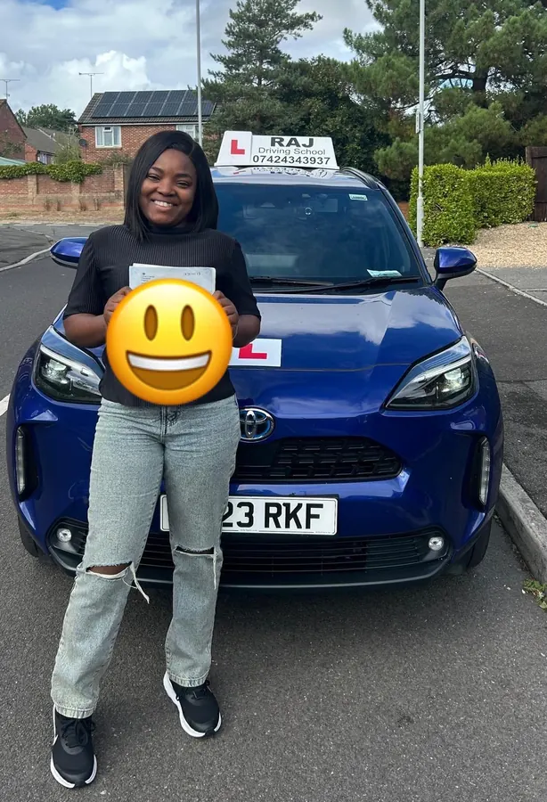 A student holding their driving test pass certificate beside Raj's Toyota Yaris Cross