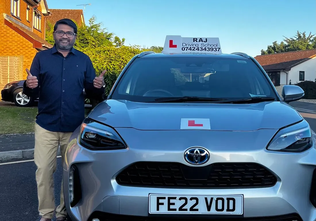 Raj, driving instructor, beside his Toyota Yaris Cross lesson car